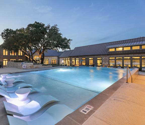 A large outdoor swimming pool with a modern design and a building in the background.