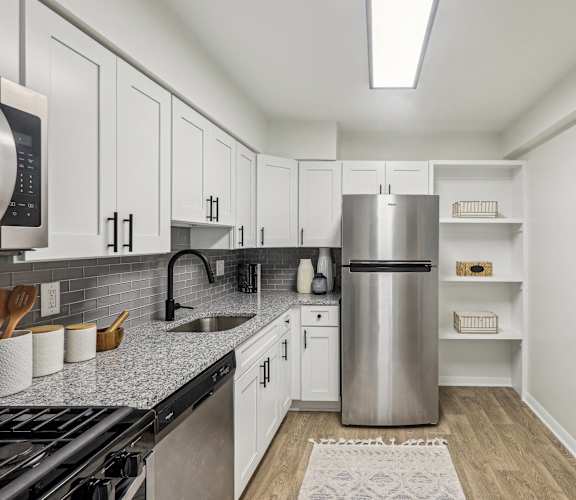 A kitchen with white cabinets and a stainless steel refrigerator.
