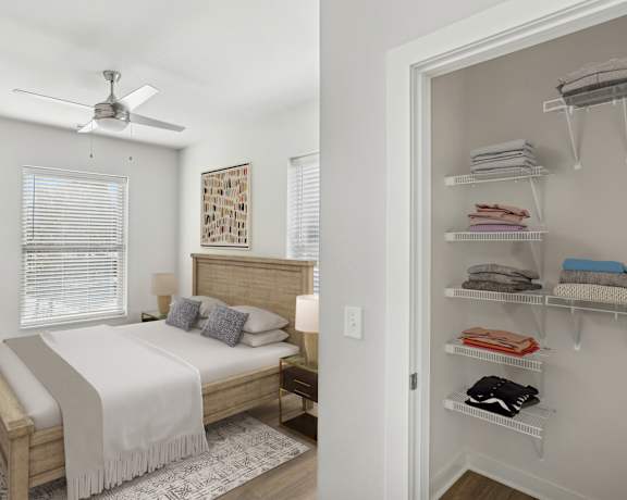 A bedroom with a bed, a fan, and a closet with clothes.