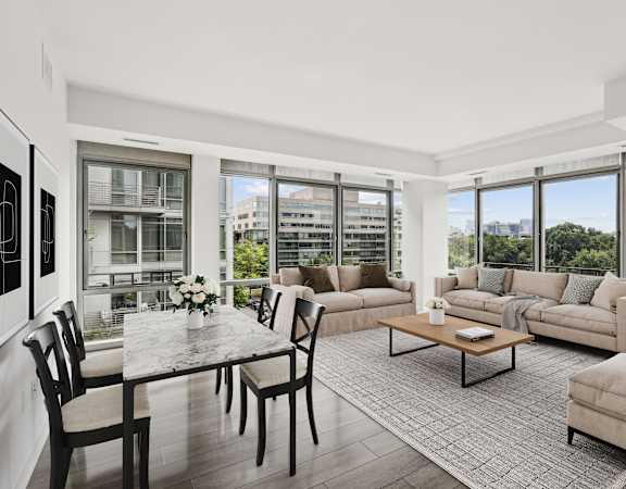 a living room with couches and a table with chairs and large windows