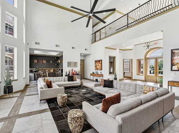 A large, modern living room with a long couch and a ceiling fan.