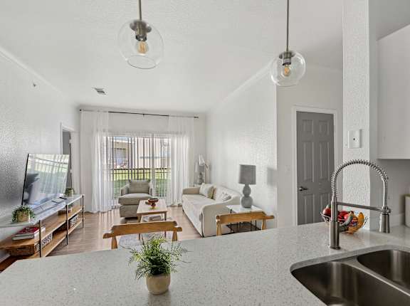 A modern kitchen with a white countertop and a stainless steel sink.