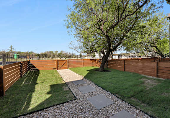 A backyard with a gravel path and a tree.