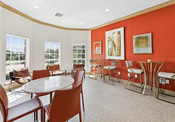 A white table surrounded by brown chairs in a room with red walls.