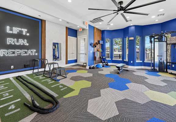 A gym with a blue wall and a sign that says "Lift. Run. Repeat."