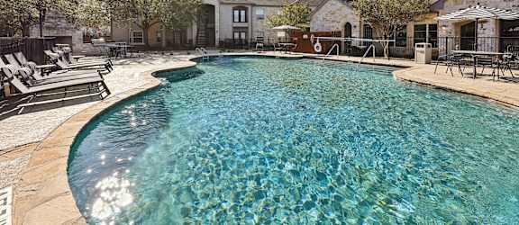 A swimming pool surrounded by chairs and buildings.