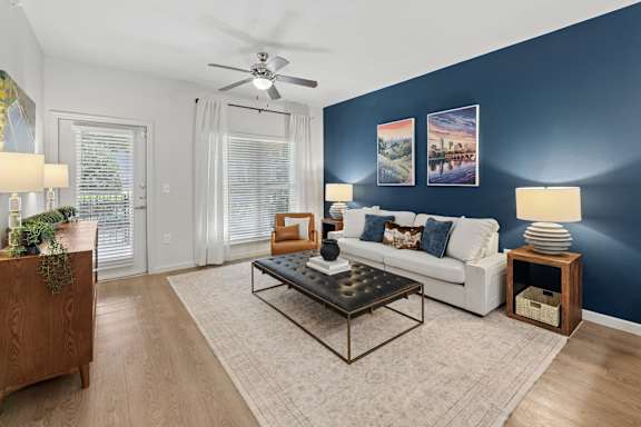 A living room with a white couch, a wooden side table, and a rug.