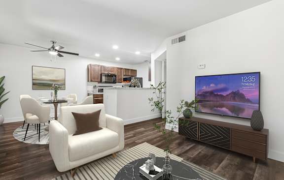 A living room with a white chair, a black coffee table, and a flat screen TV mounted on the wall.