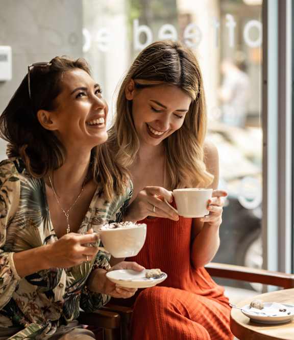 Two women enjoying a cup of coffee together in a cafe at 100 South Apartments, Buffalo, NY 14202