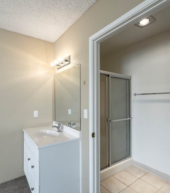 A bathroom with a sink, mirror, and shower.