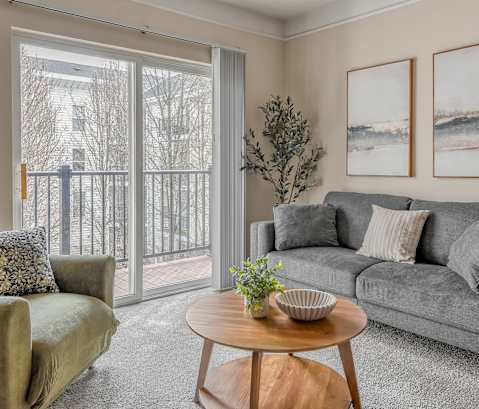 A living room with a grey couch, a green chair, a wooden coffee table, and two framed pictures on the wall.