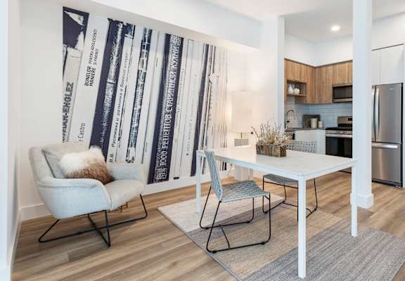 dining area and kitchen with white walls and a poster 