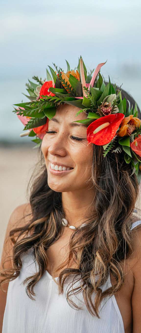 A woman with a flower crown on her head is smiling.