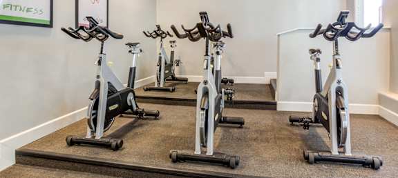 A room with a wall that says Fitness and a row of stationary bikes.