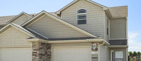 A house with a garage door and a stone pillar.