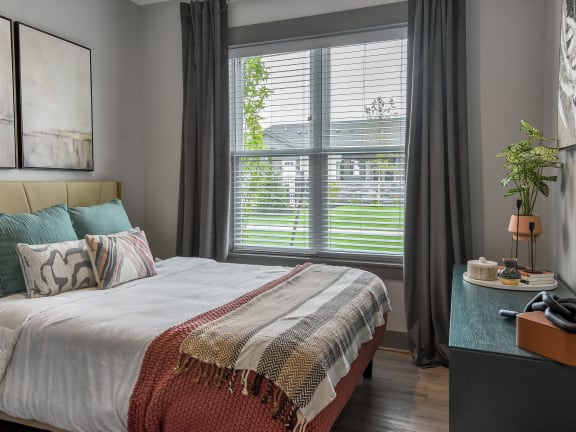 a bedroom with a bed and a large window at The Commons at Rivertown, Michigan