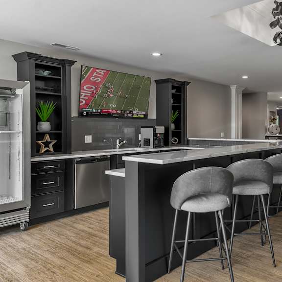 a kitchen with a bar and stools and a tv