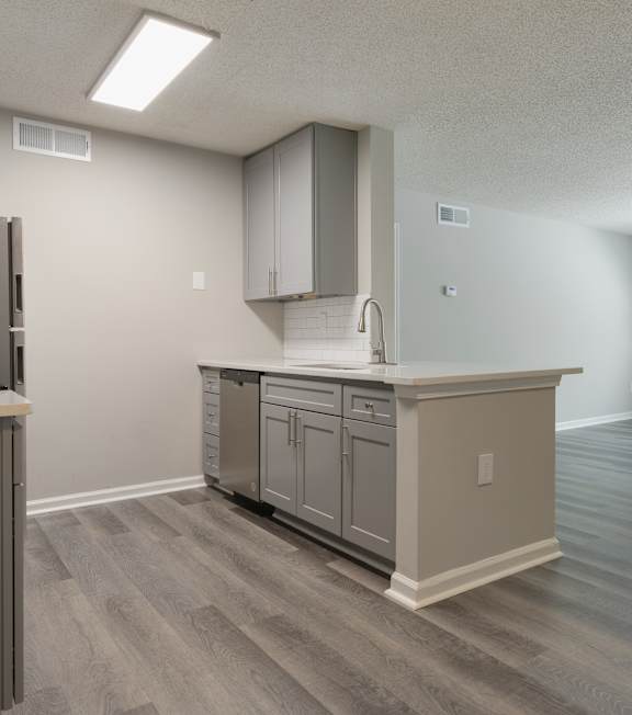 A kitchen with a refrigerator, cabinets, and a countertop.