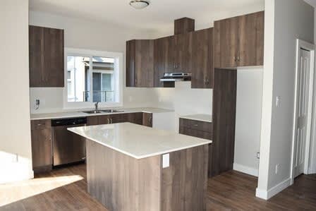 A modern kitchen with a white countertop and wooden cabinets.