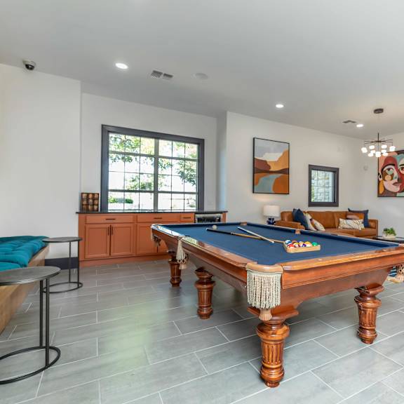 A pool table is in the middle of a room with a blue cloth on it.