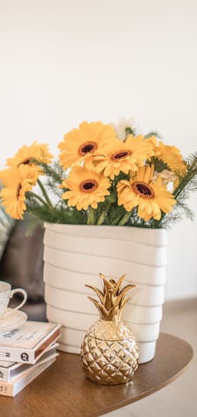 A table with a stack of books, a cup of tea, a pineapple, and a vase of flowers at Tigardville Apartments, OR, 97223