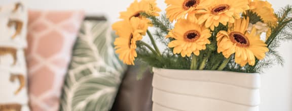 A white vase with yellow flowers sits on a table at Coast Pine
