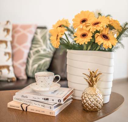a vase of sunflowers on a coffee table with books and a pineapple