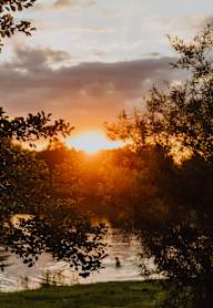 A beautiful sunset over a river with people swimming.