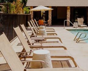 a row of wooden lounge chairs next to a pool