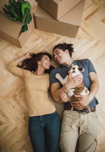 high angle view of a young couple lying on the floor with their dog and looking up at