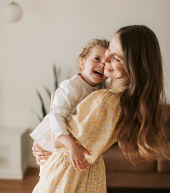 A woman in a yellow dress holds a child in her arms.