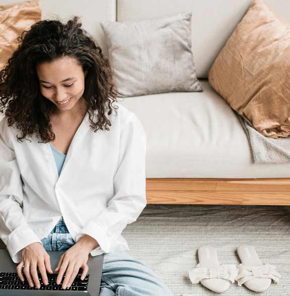 A woman in a white robe is sitting on the floor using a laptop.