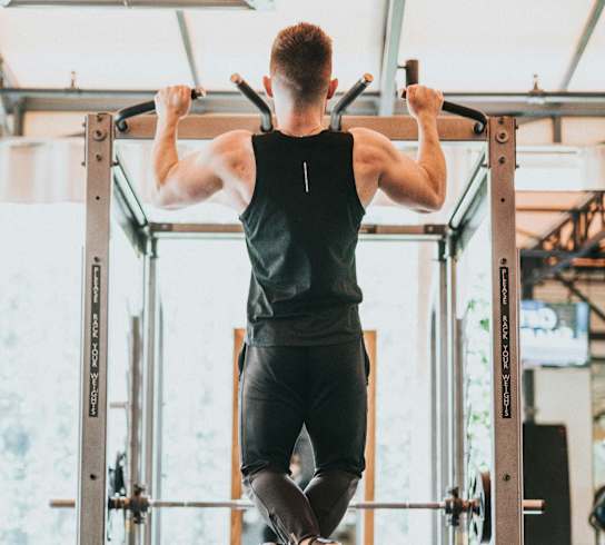 A man doing pull-ups on a gym machine at The Bessemer at Seward Commons Apartments, Minneapolis, MN,  55404