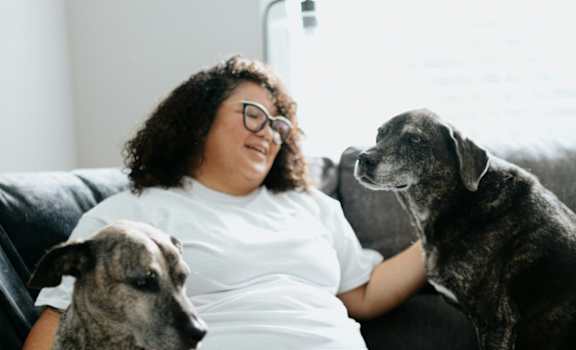 A woman is sitting on a couch with two dogs.