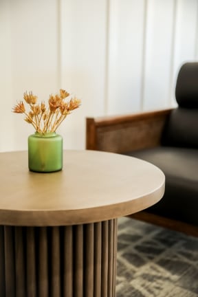 a small table with a green vase of dried flowers on top