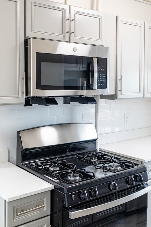 A modern kitchen with a stove and microwave above it.