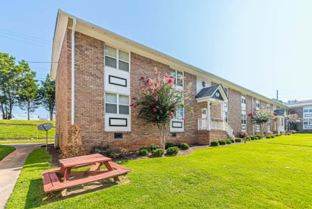 a living room with a glass table and a kitchen with stainless steel appliances at Georgian Oaks Apartments, Smyrna , Georgia