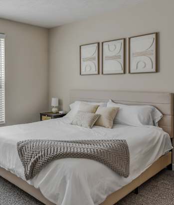 A bedroom with a bed, nightstand, and window with blinds.