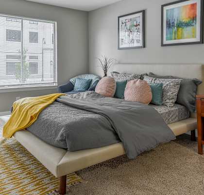 a bedroom with a bed with pillows and a blanket on it at The Pointe at St. Joseph Apartments, South Bend, 46617