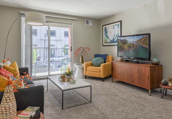 an apartment living room with a tv and a sliding glass door at The Pointe at St. Joseph Apartments, South Bend, IN, 46617