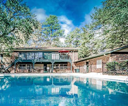 A large swimming pool in front of a house with a deck.