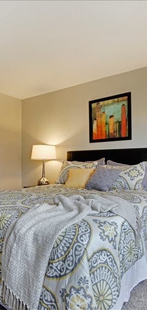 A bed with a white blanket and a painting on the wall. at Oakwood, Plymouth, 55447