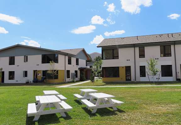 a group of white houses with picnic tables in the grass