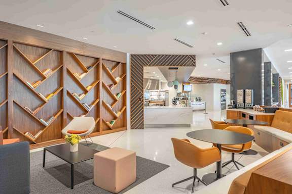 A modern dining area with a glass table and orange chairs.