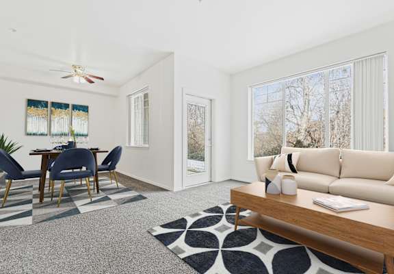 a living room with white walls and a sliding glass door leading to a dining room with a