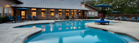 a swimming pool with chairs and a building in the background