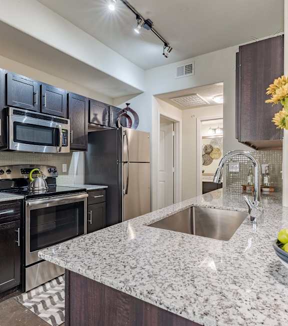 Kitchen Counter with Sink and Cabinetry with Decor a bedroom with a bed and a ceiling fan