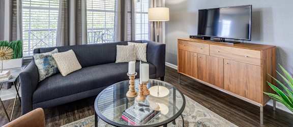 a living room with a couch and a glass coffee table and a television