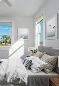 A bedroom with a bed, a ceiling fan, and a potted plant.