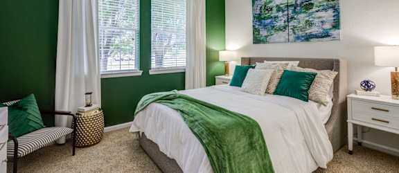 a bedroom with green walls and a bed with a large window